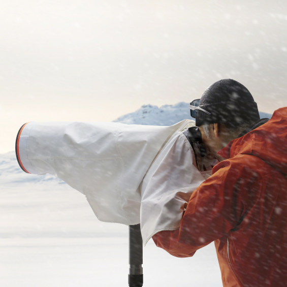 Een man fotografeert in de sneeuw met de regenhoes van Sony