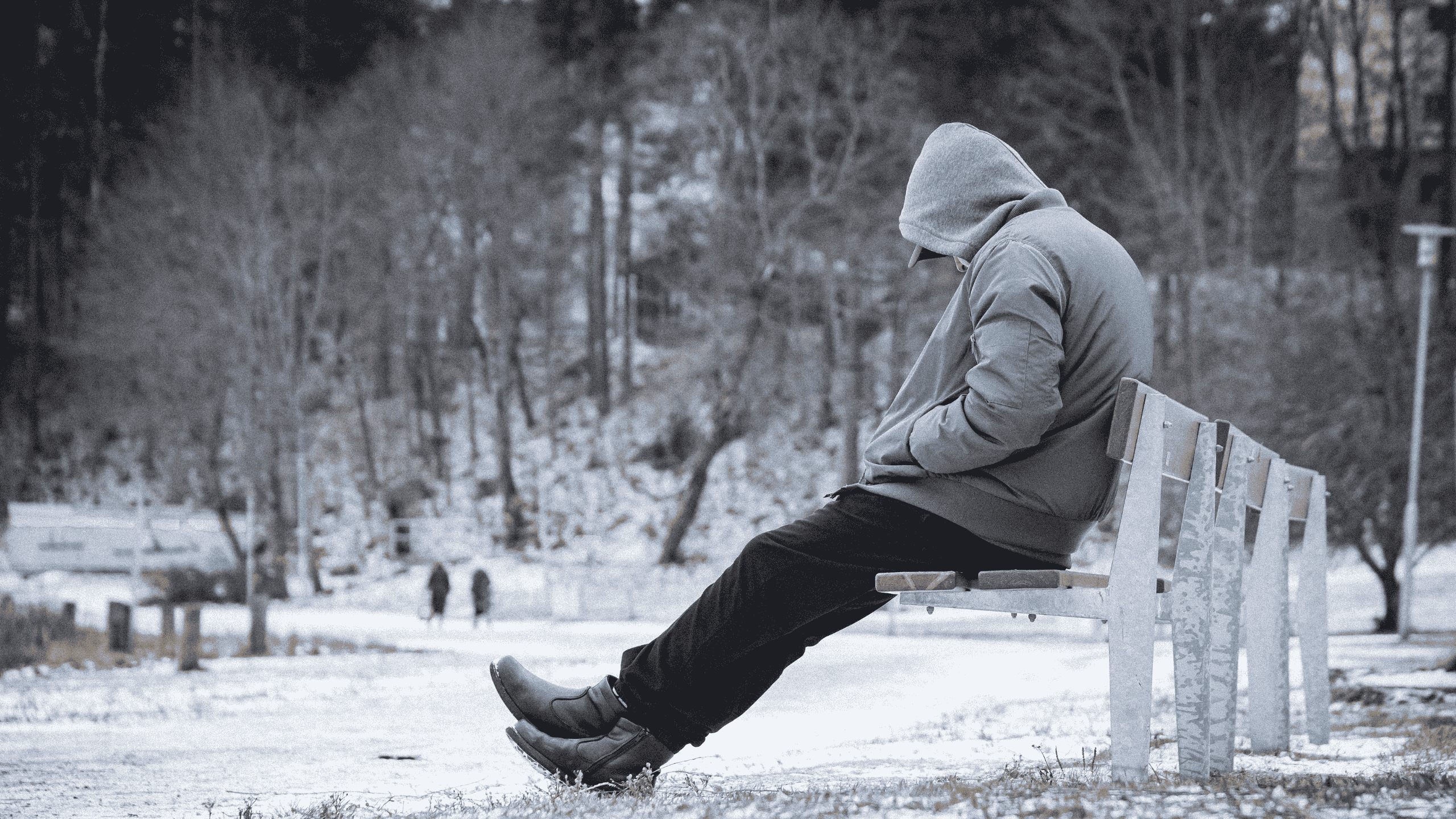 Een man die alleen zit op een bankje in de winter