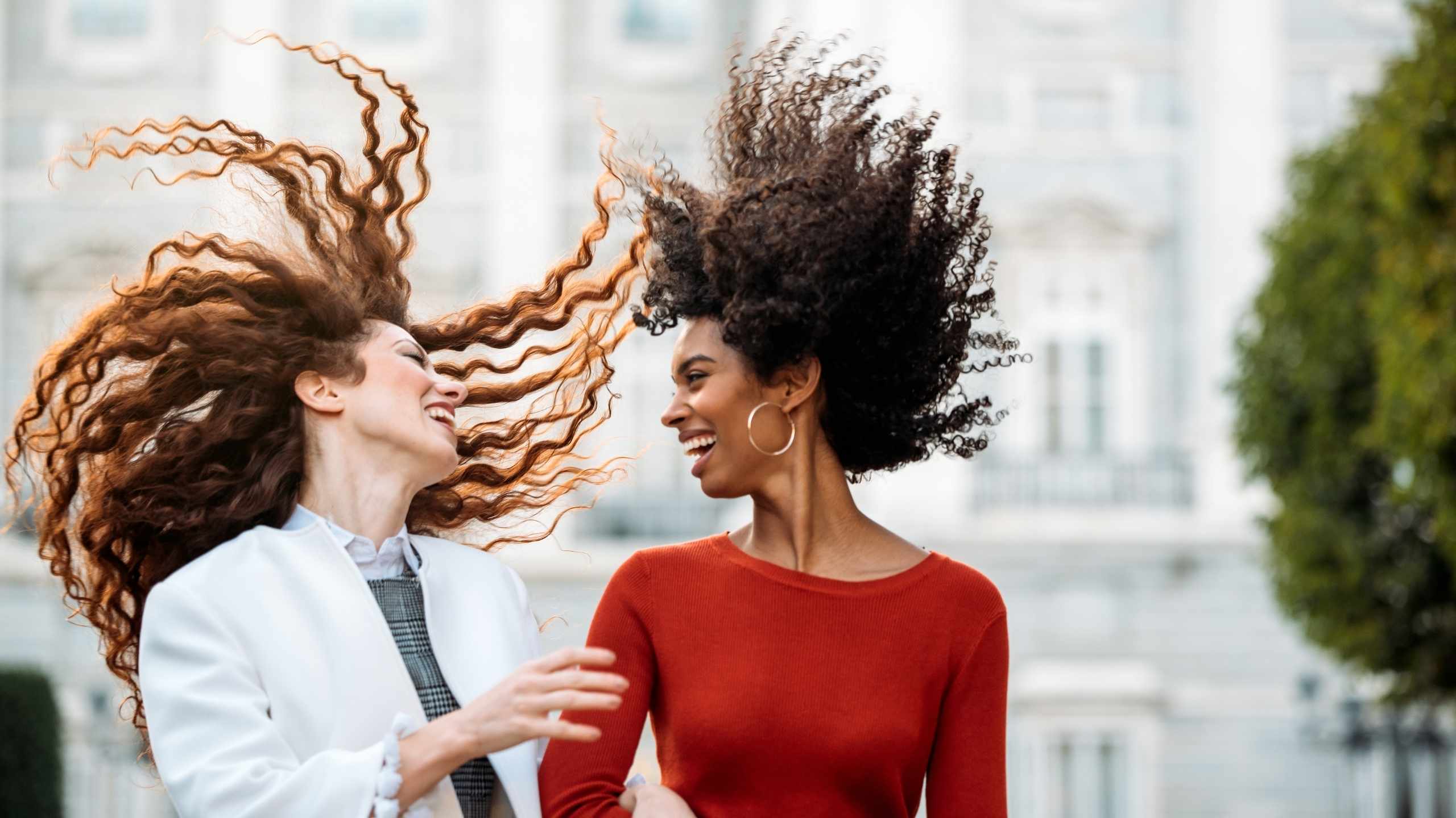 Vrouwen die lachen springen met krullend haar